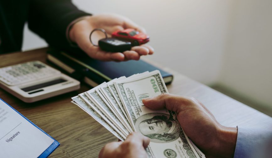 New car buyers are holding cash and handing it to car salespeople while filing a new car signing contract for car buyers.