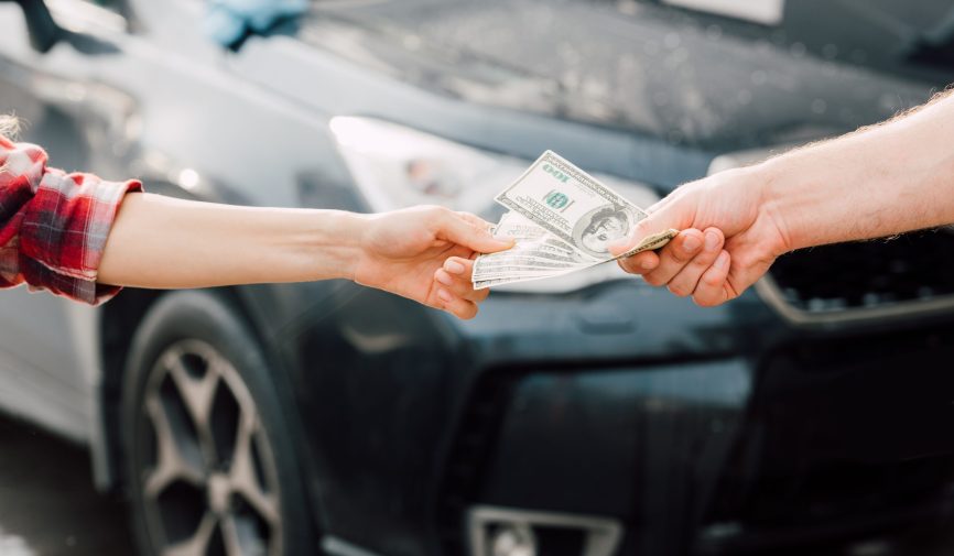 cropped view of man giving money to woman near car