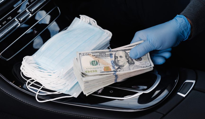 Virus concept. Hand in rubber gloves holds stack of dollar banknotes, earns money as sells medical masks, poses in car. Covid epidemic. Speculation at market of necessary products. Quarantine period