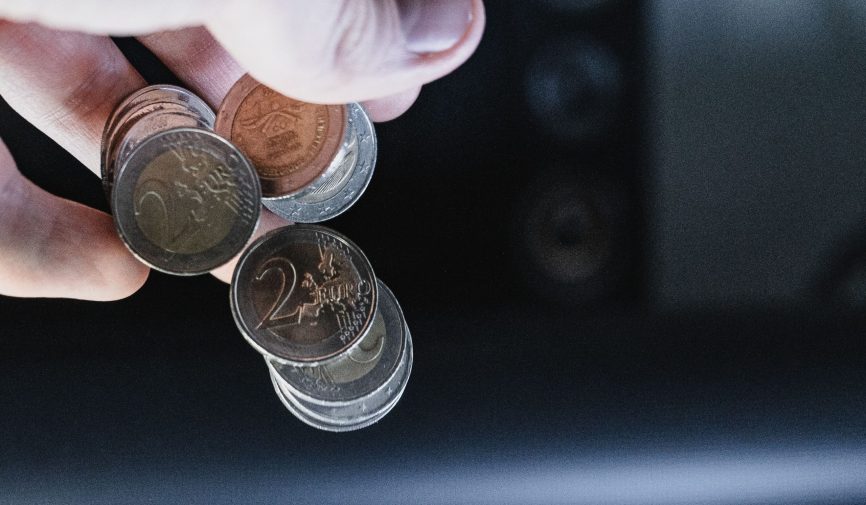 A closeup shot of a hand pouring out a couple of two Euro coins