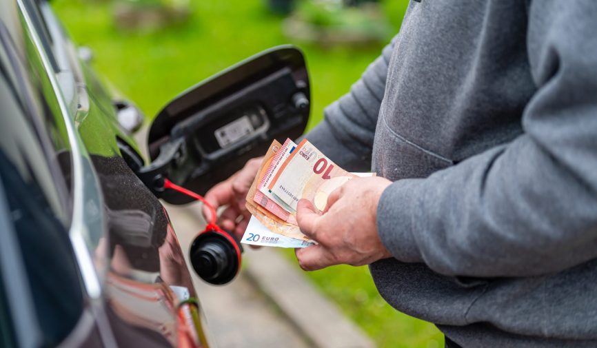 a man s hand counts money while standing at an open fuel tank, the concept of rising fuel prices