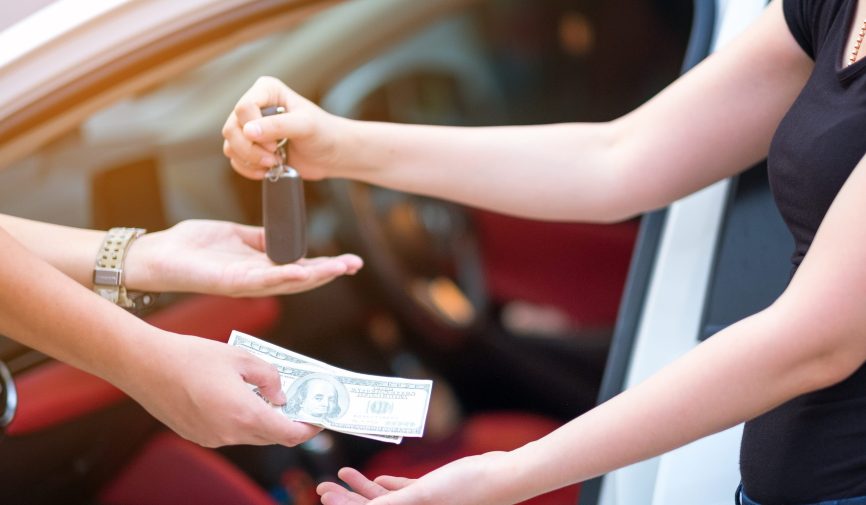 woman in showroom giving dollars money and taking keys from car