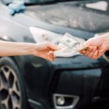 cropped view of man giving money to woman near car