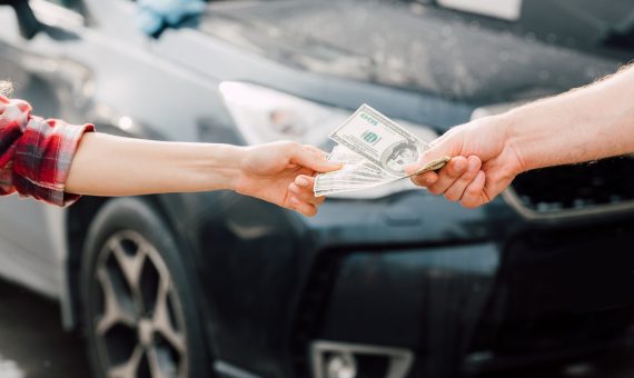 cropped view of man giving money to woman near car